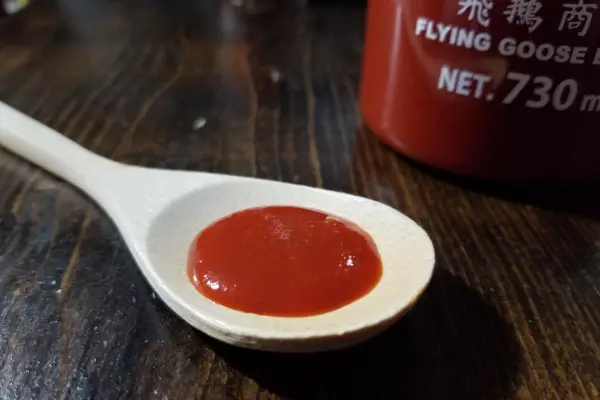 Flying Goose Brand Original Sriracha sauce on a spoon to show texture.